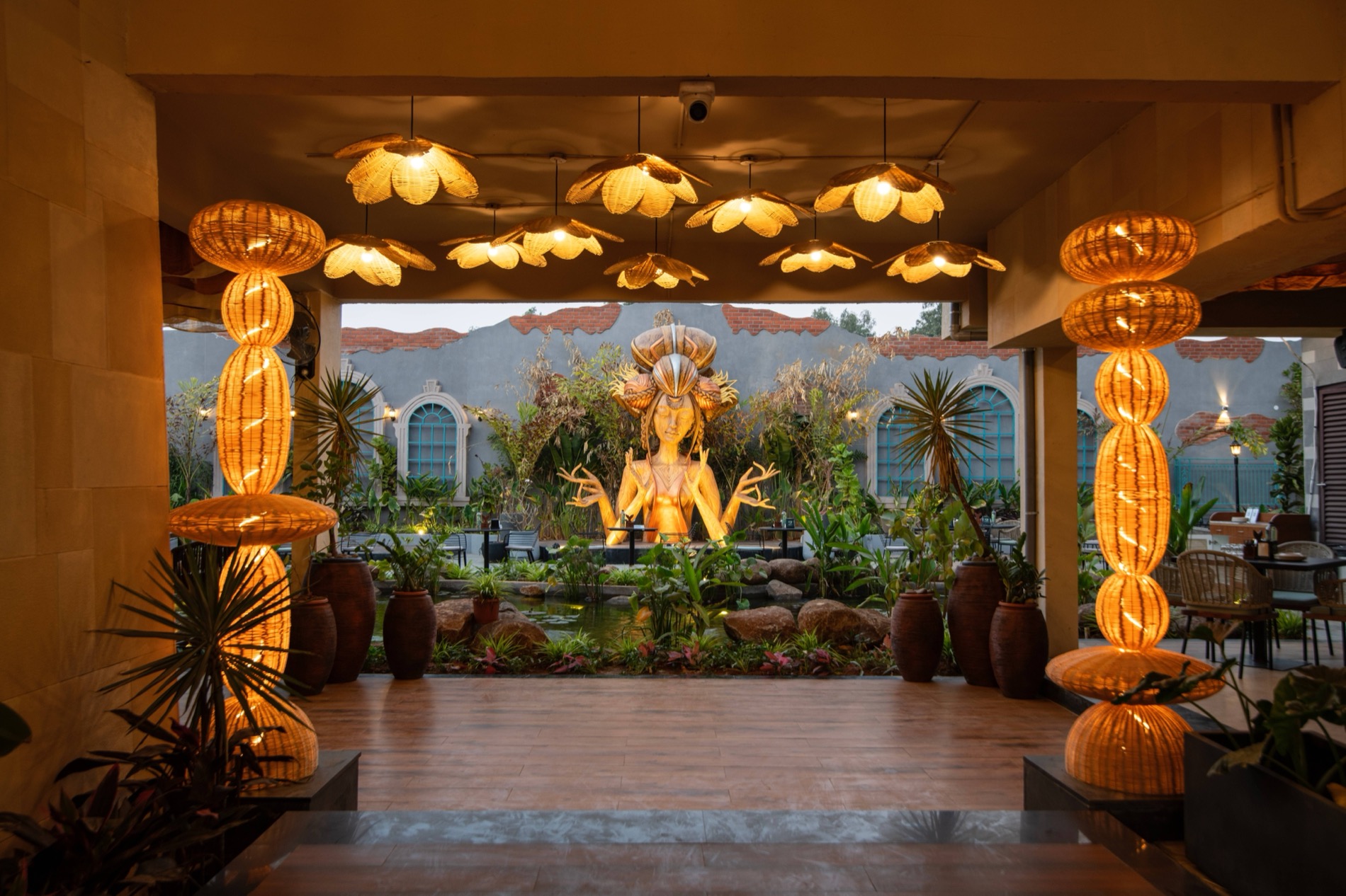 Rattan lotus lights framing the golden goddess statue at dusk